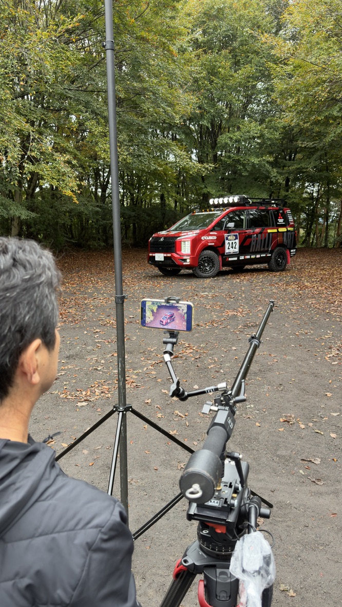木々を背景にした赤い車両と手前の撮影機材