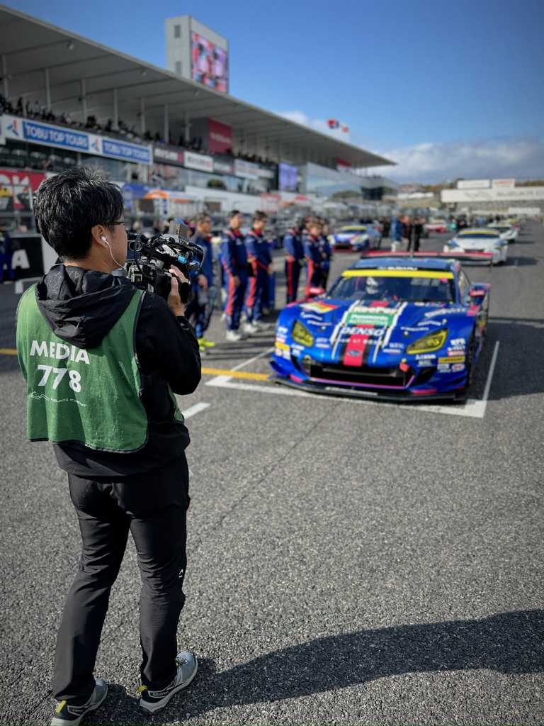 サーキットのグリッドで車両とチームを撮影するカメラマン